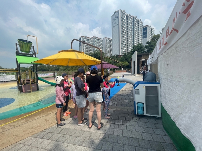 화성시에서 제공한 버스승강장 및 공원 등에 설치된 냉난방기 앞에 어린 자녀들과 함께 서 있는 부모님들 모습